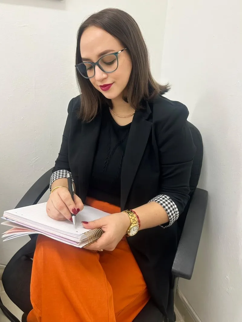 Luisa M. Reyes P. escribiendo en una libreta, con la mirada puesta en sus notas
